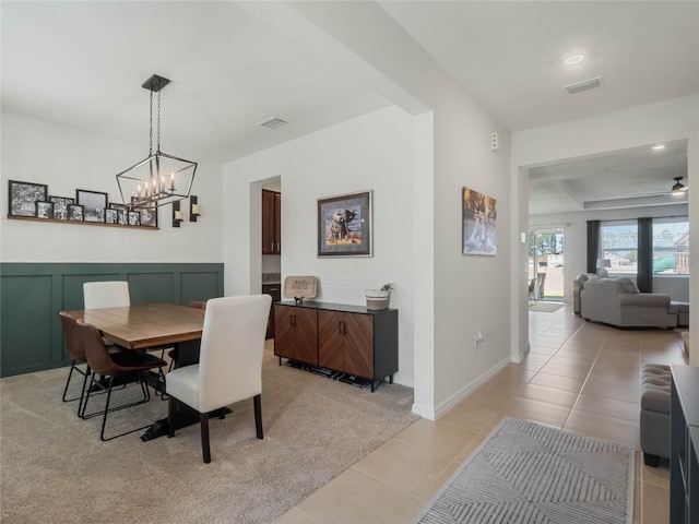 dining room with wainscoting, light tile patterned flooring, visible vents, and a decorative wall