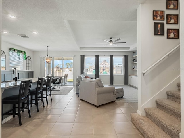 living area featuring baseboards, visible vents, stairway, a textured ceiling, and light tile patterned flooring