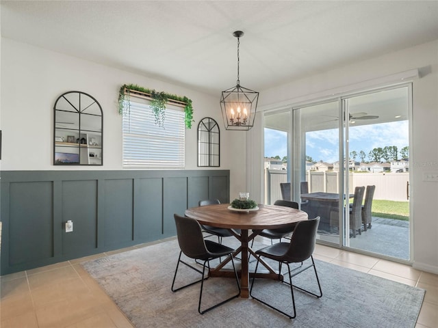 dining area featuring a chandelier, wainscoting, light tile patterned flooring, and a decorative wall