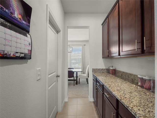 kitchen with light stone counters, light tile patterned flooring, and baseboards