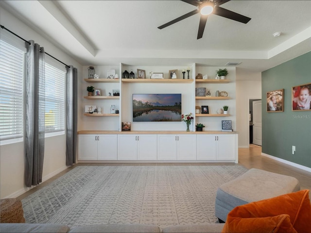 living area featuring baseboards, a ceiling fan, visible vents, and built in features