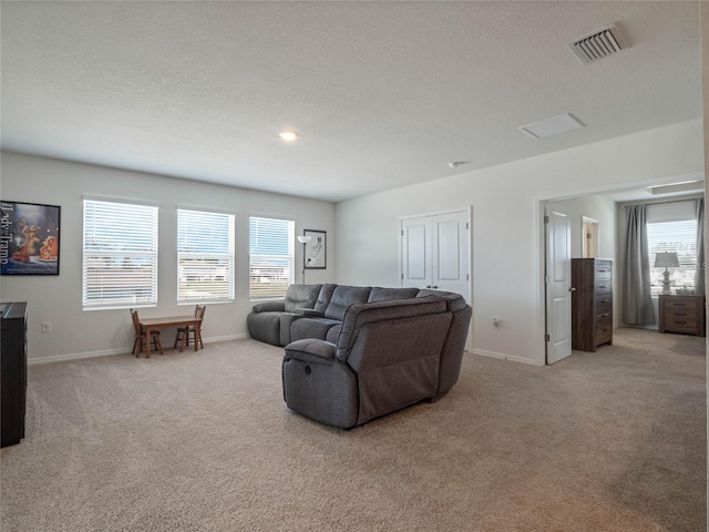 carpeted living room with a textured ceiling, visible vents, and baseboards