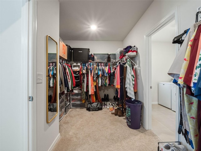 walk in closet featuring carpet floors, washer and clothes dryer, and tile patterned floors