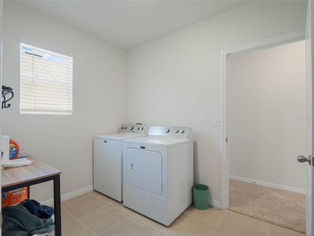 washroom featuring light tile patterned floors, laundry area, washing machine and dryer, and baseboards