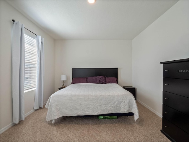 bedroom featuring light carpet and baseboards