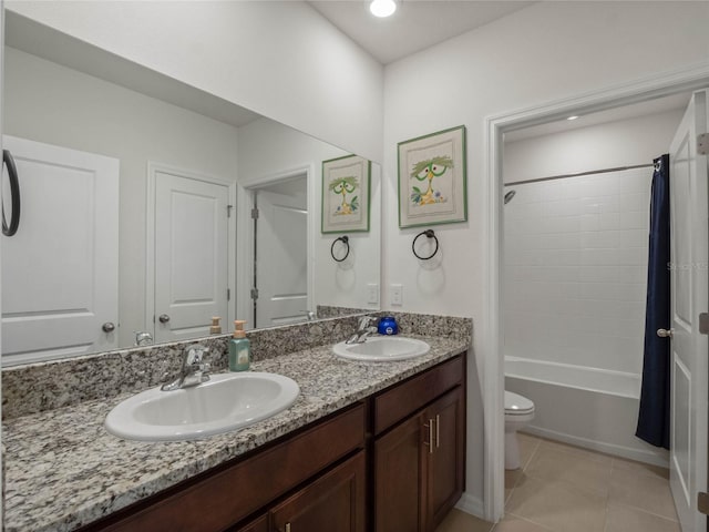 bathroom featuring toilet, double vanity, a sink, and tile patterned floors