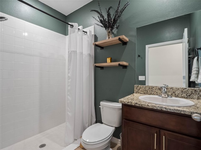 full bathroom featuring toilet, a stall shower, and vanity