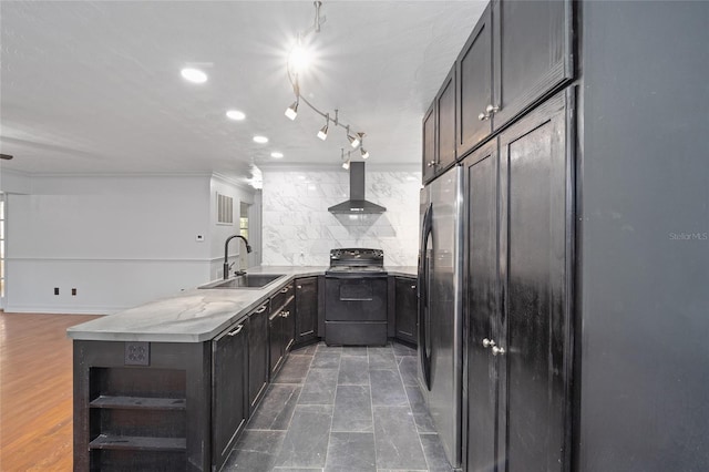 kitchen with decorative backsplash, a peninsula, wall chimney range hood, black range with electric cooktop, and a sink