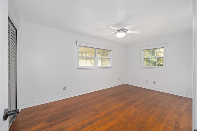 unfurnished room with baseboards, dark wood finished floors, and a ceiling fan