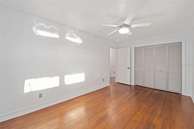 unfurnished bedroom with a closet, wood finished floors, a ceiling fan, and baseboards