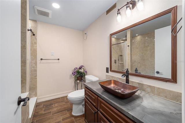 full bathroom with wood finish floors, visible vents, a tile shower, and toilet