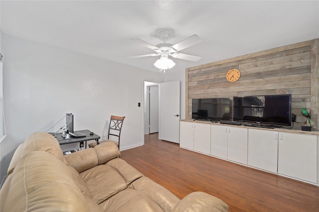 living area featuring ceiling fan, baseboards, and wood finished floors