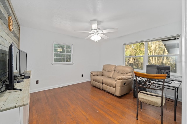 living area featuring ceiling fan, a fireplace, baseboards, and wood finished floors