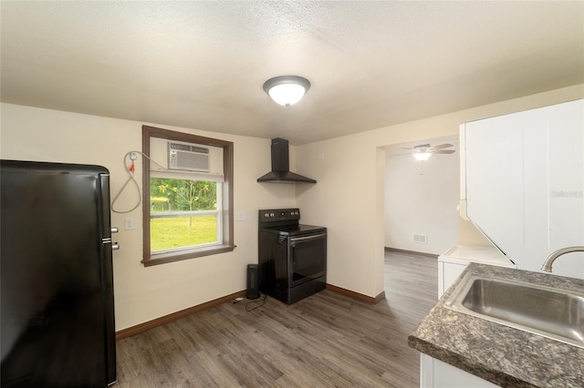 kitchen with a wall unit AC, dark wood-type flooring, wall chimney range hood, black appliances, and a sink