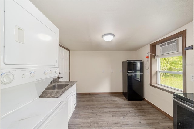 kitchen featuring stainless steel electric range oven, freestanding refrigerator, light wood-type flooring, stacked washing maching and dryer, and white cabinetry