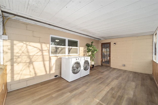 laundry area featuring laundry area, wood finished floors, washing machine and dryer, and concrete block wall