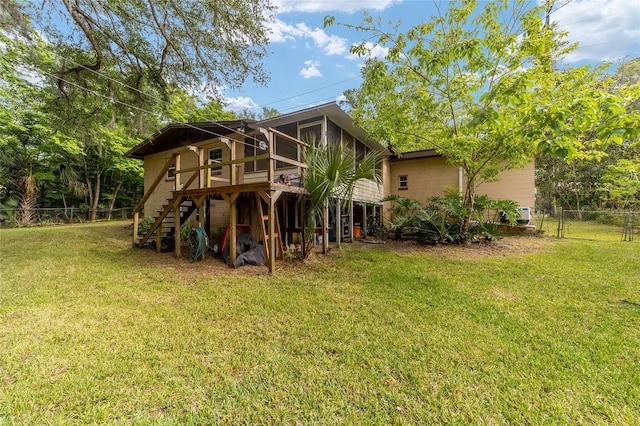 back of property with a deck, fence, a sunroom, a lawn, and stairway