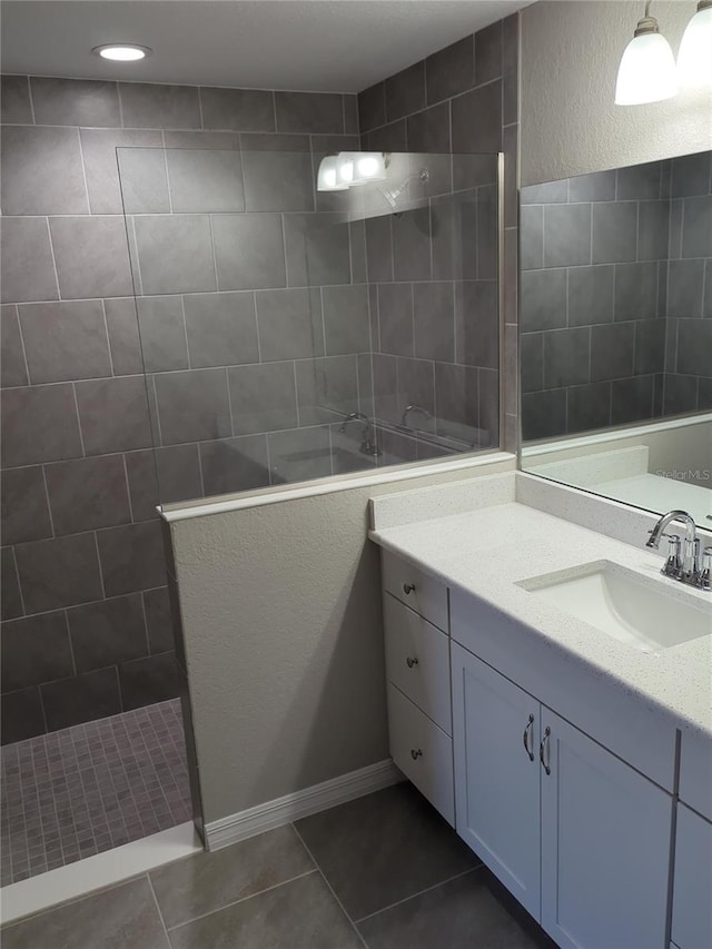 full bathroom with a walk in shower, vanity, and tile patterned floors