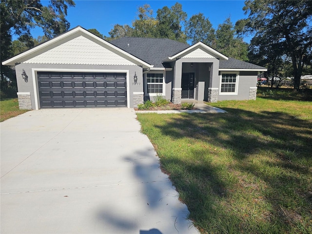 view of front of property with a garage, a front yard, stone siding, and driveway