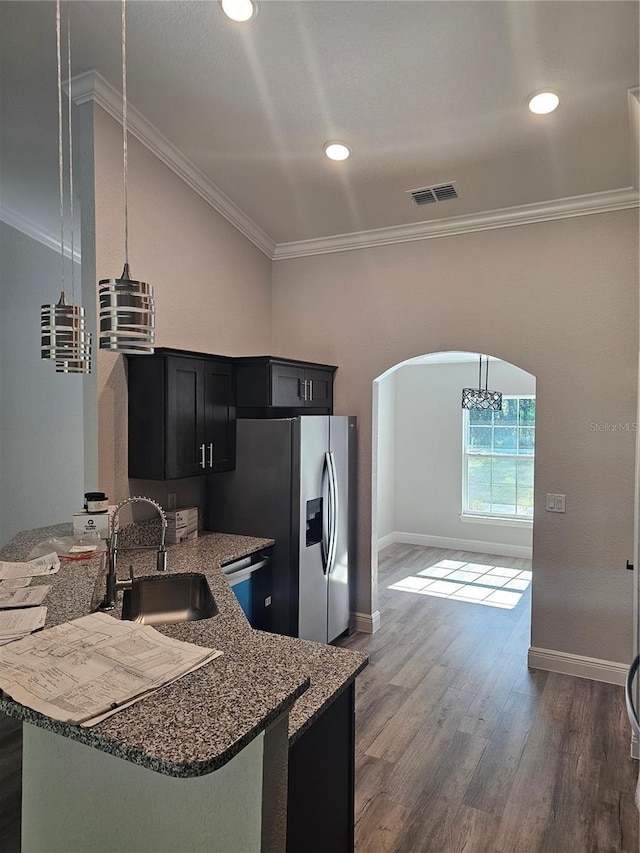 kitchen with arched walkways, crown molding, visible vents, a sink, and dark cabinets