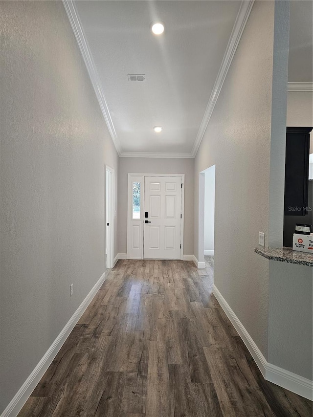 entryway with crown molding, visible vents, a textured wall, wood finished floors, and baseboards