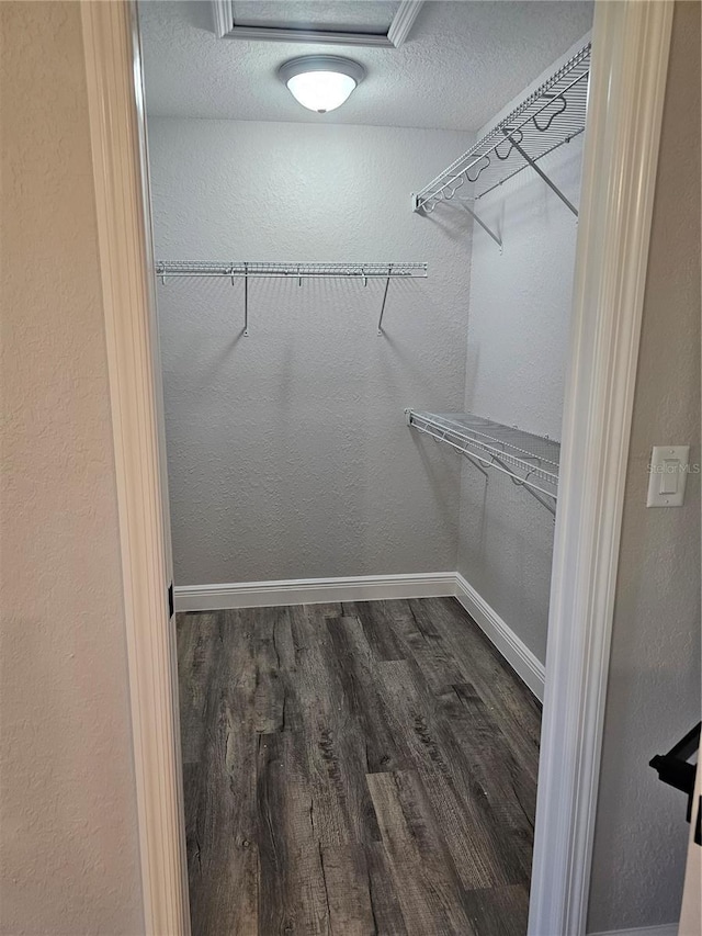 walk in closet with wood finished floors and attic access