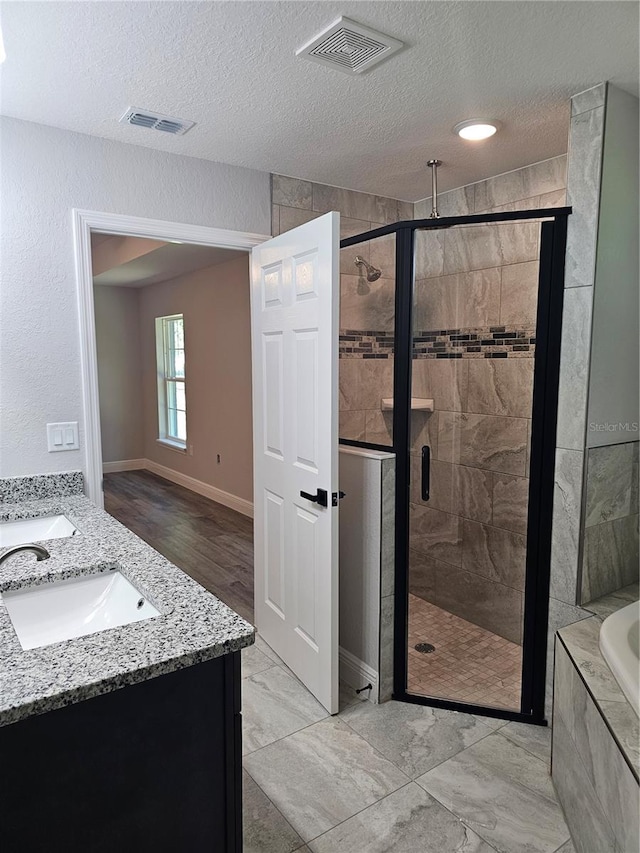 bathroom with a stall shower, a sink, and visible vents