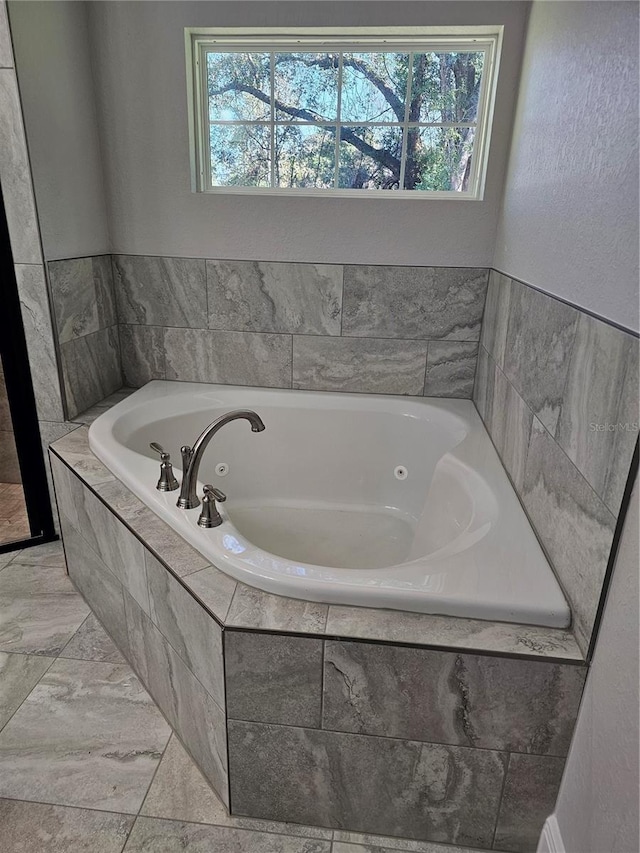 bathroom with a garden tub and a healthy amount of sunlight