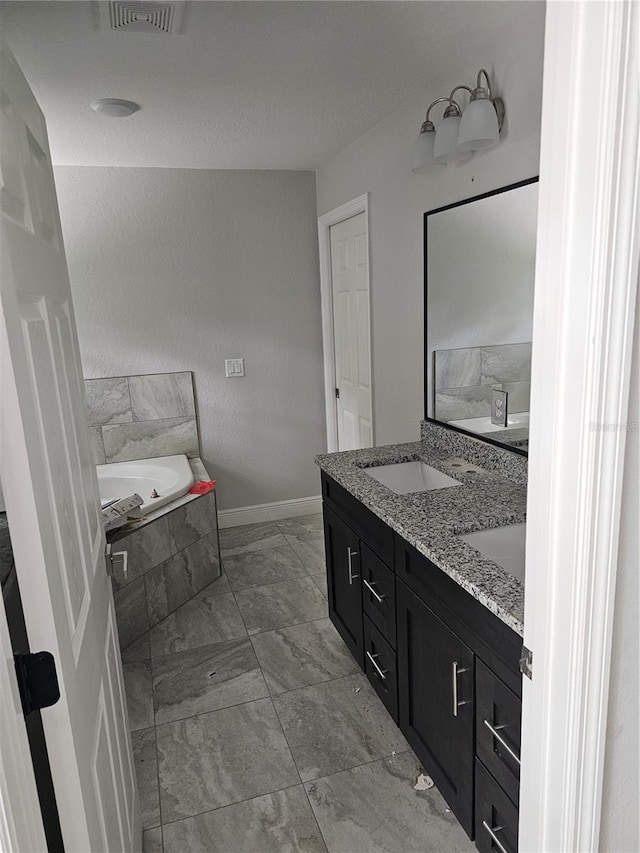 bathroom with a garden tub, a sink, visible vents, baseboards, and double vanity