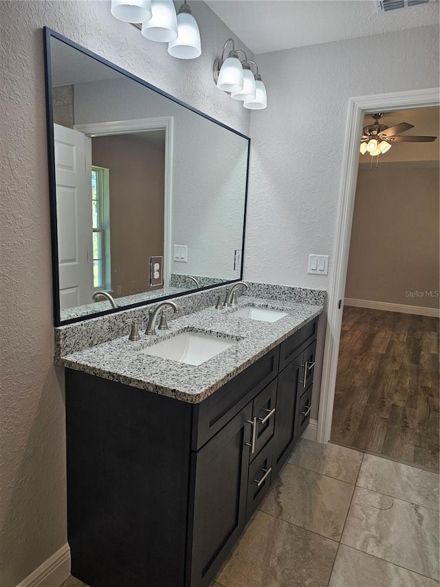 bathroom with a textured wall, double vanity, and a sink