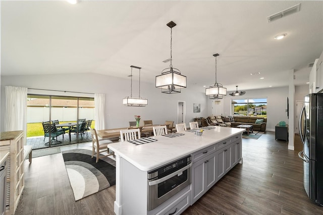 kitchen featuring visible vents, lofted ceiling, open floor plan, stainless steel appliances, and light countertops