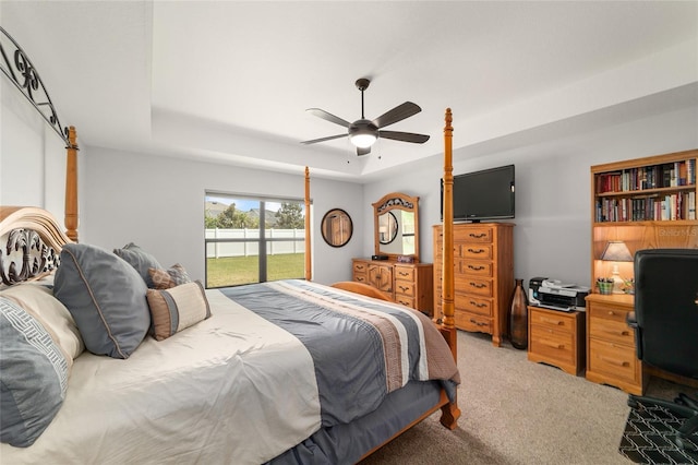 bedroom featuring a ceiling fan, access to outside, light colored carpet, and a tray ceiling