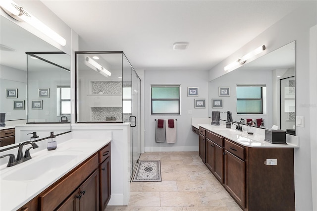 bathroom featuring two vanities, a stall shower, a healthy amount of sunlight, and a sink