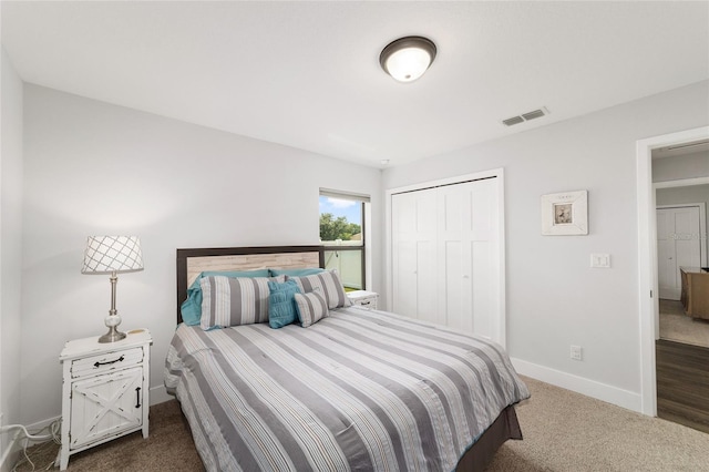 bedroom with dark colored carpet, a closet, visible vents, and baseboards