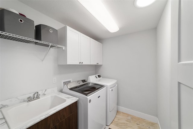 laundry room featuring cabinet space, washing machine and dryer, baseboards, and a sink