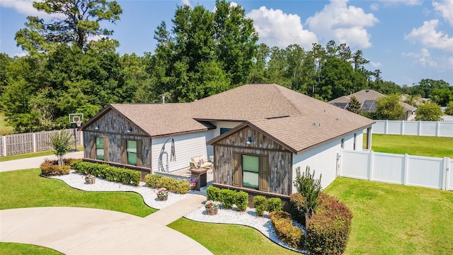 view of front of property featuring a front yard, a fenced backyard, driveway, and roof with shingles