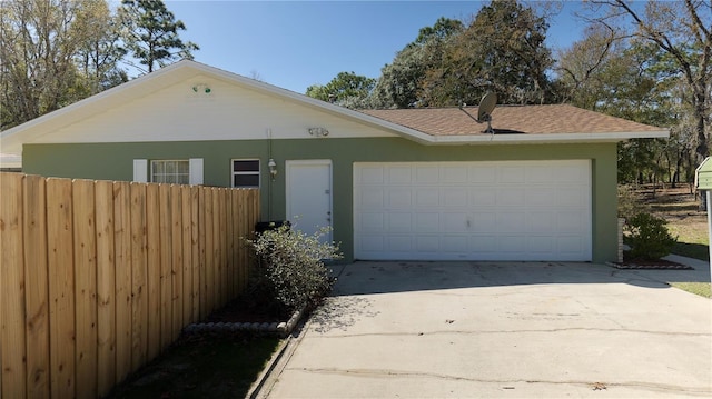 view of front of property featuring an attached garage, driveway, fence, and stucco siding