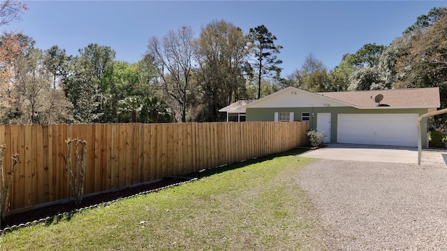 view of yard featuring a garage, gravel driveway, and fence