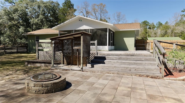 rear view of property with a wooden deck, a sunroom, and fence