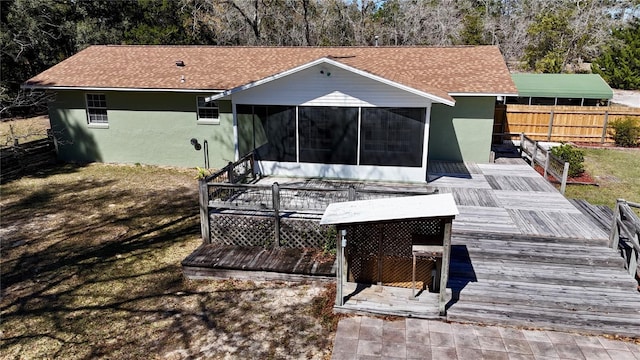 back of property featuring a sunroom, fence, a deck, and stucco siding