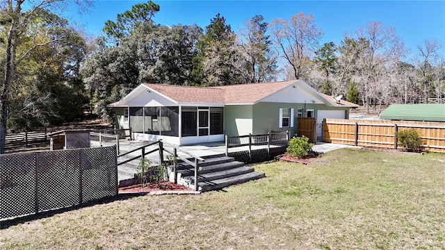 back of house with a sunroom, a lawn, a wooden deck, and fence