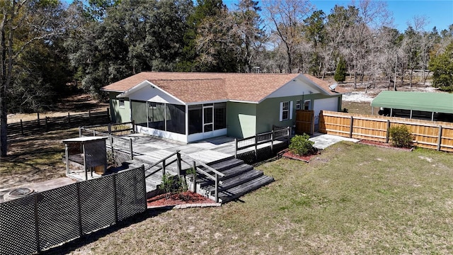 rear view of house with a yard, stucco siding, a sunroom, fence private yard, and a wooden deck