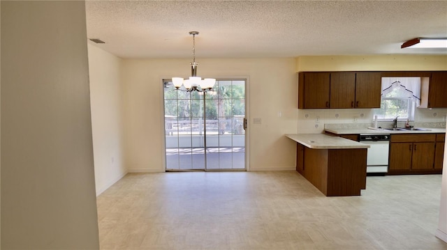 kitchen featuring visible vents, dishwasher, a peninsula, light countertops, and a sink