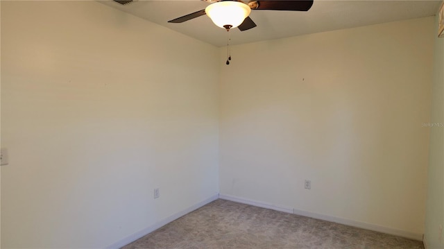 spare room featuring light carpet, ceiling fan, visible vents, and baseboards