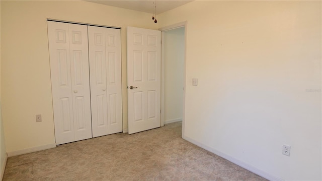 unfurnished bedroom featuring light carpet, baseboards, and a closet