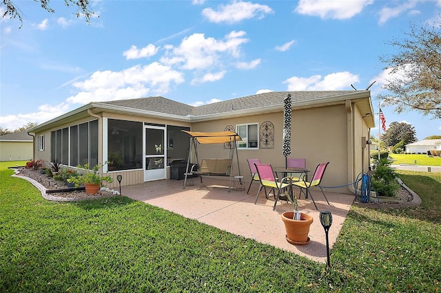 rear view of property featuring a sunroom, a patio area, a lawn, and stucco siding