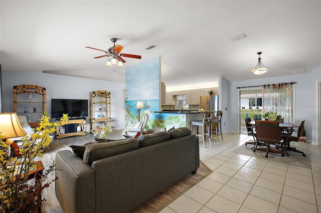 living room with visible vents, vaulted ceiling, a ceiling fan, and light tile patterned flooring