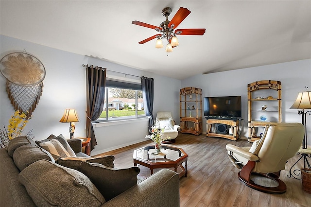 living room featuring ceiling fan, baseboards, vaulted ceiling, and wood finished floors