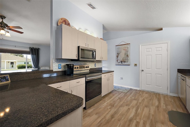 kitchen with visible vents, dark countertops, vaulted ceiling, stainless steel appliances, and light wood-type flooring