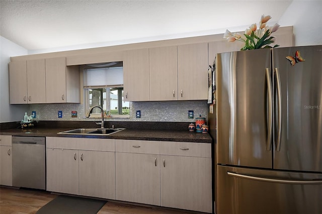 kitchen with stainless steel appliances, a sink, decorative backsplash, and wood finished floors